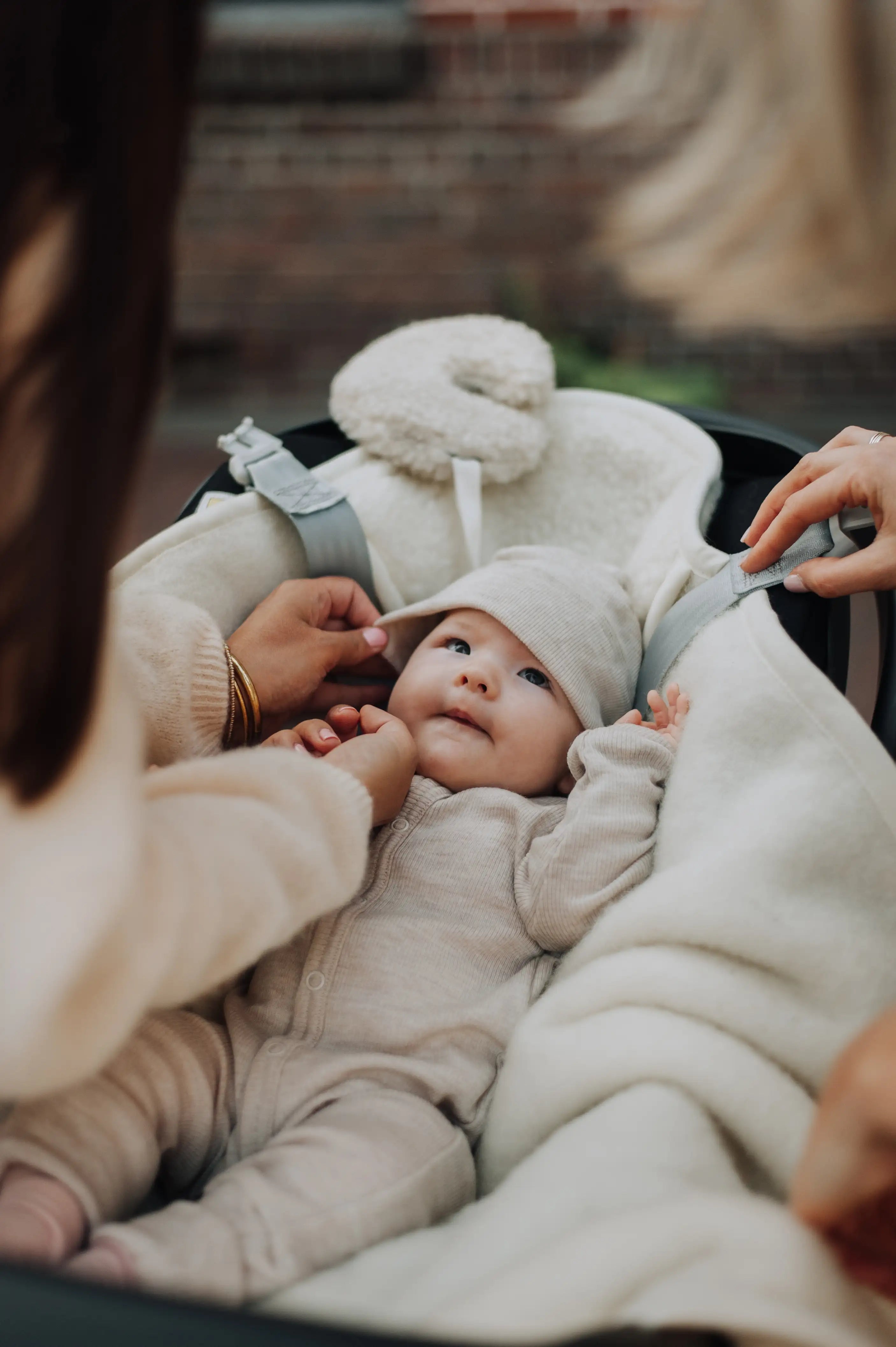 Baby met muts in een maxi cosi met een wollen knuffel in de vorm van een maan