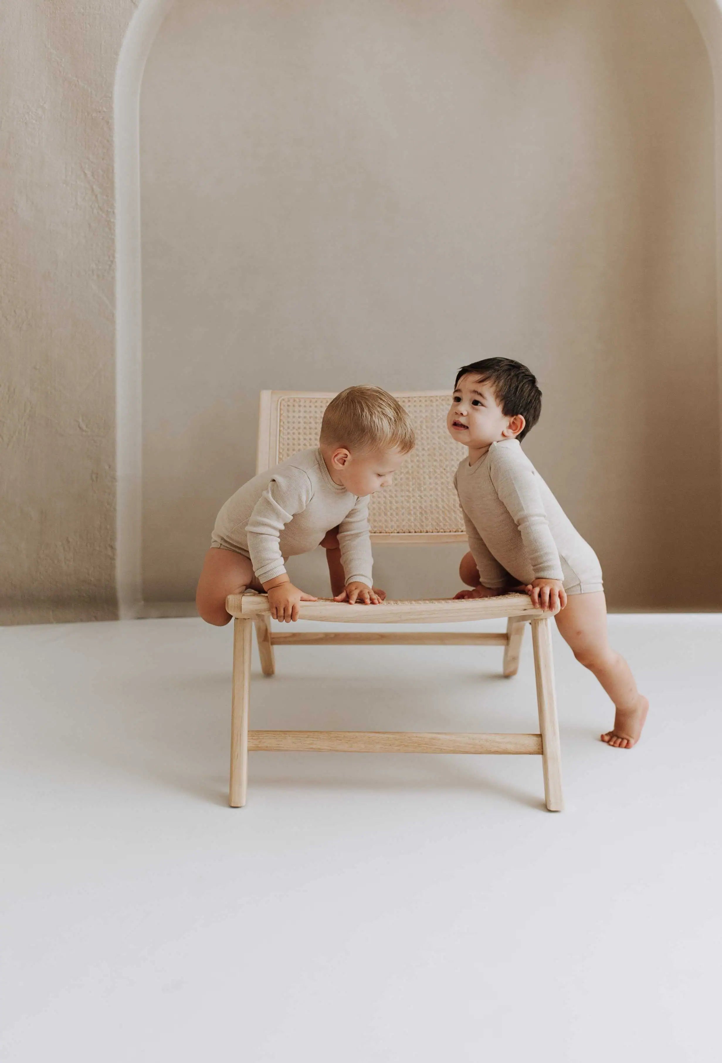 Twee bay's klimmend op een stoel in rompers. Professionele fotoshoot