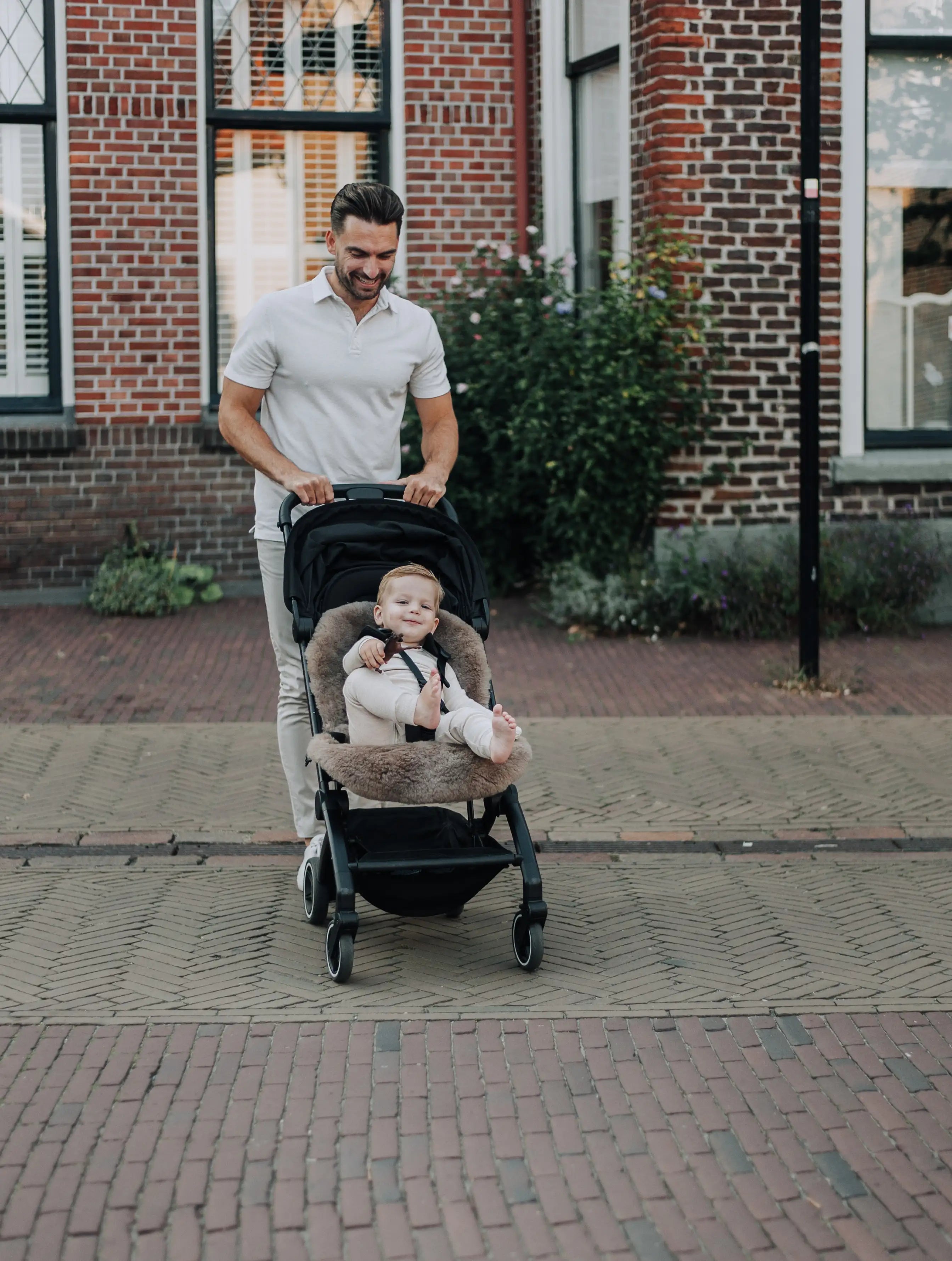 Vader met zoon in een kinderwagen die ligt op een wollen schapenvacht