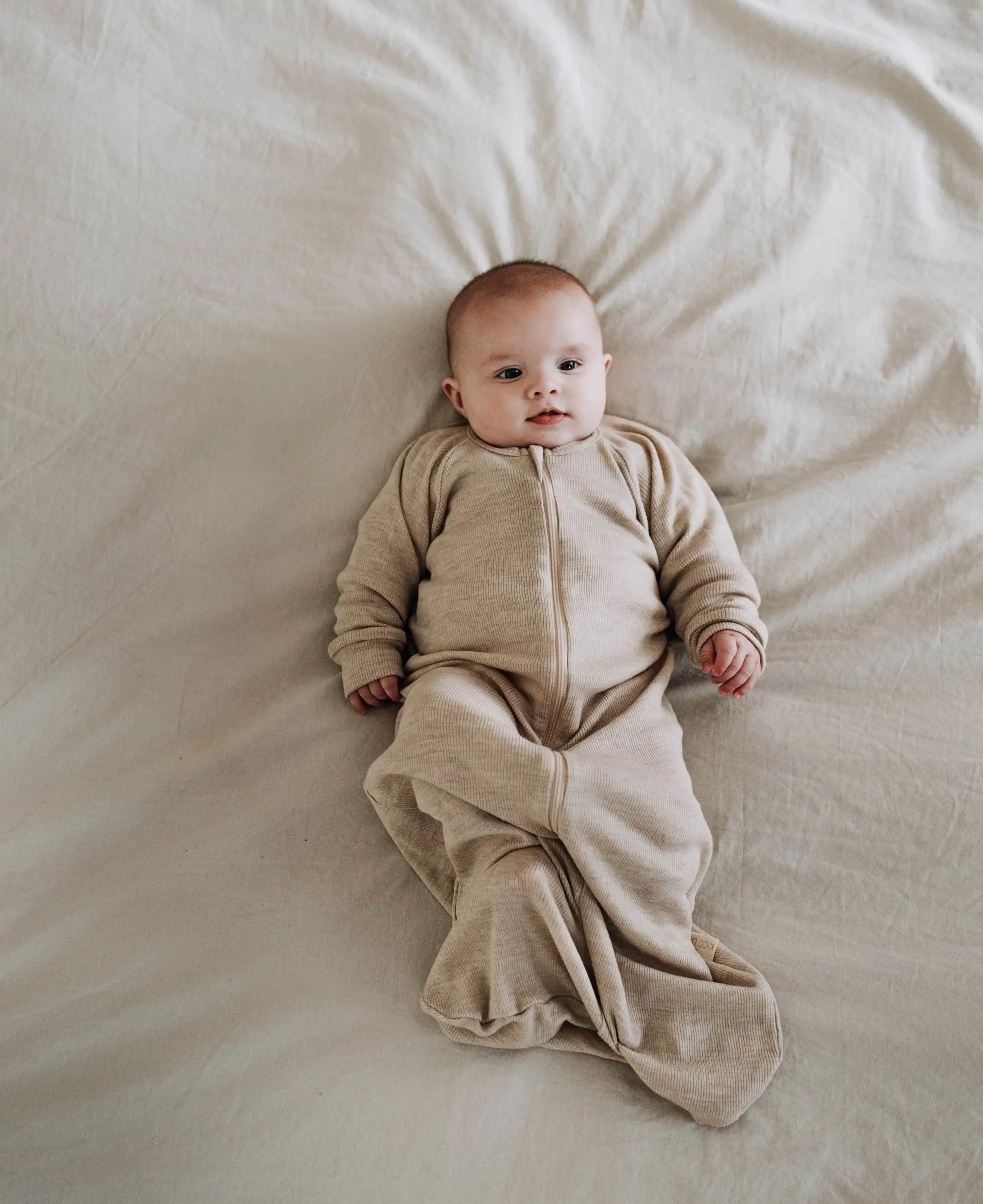 Baby die in slaapzak van wol ligt op zijn rug