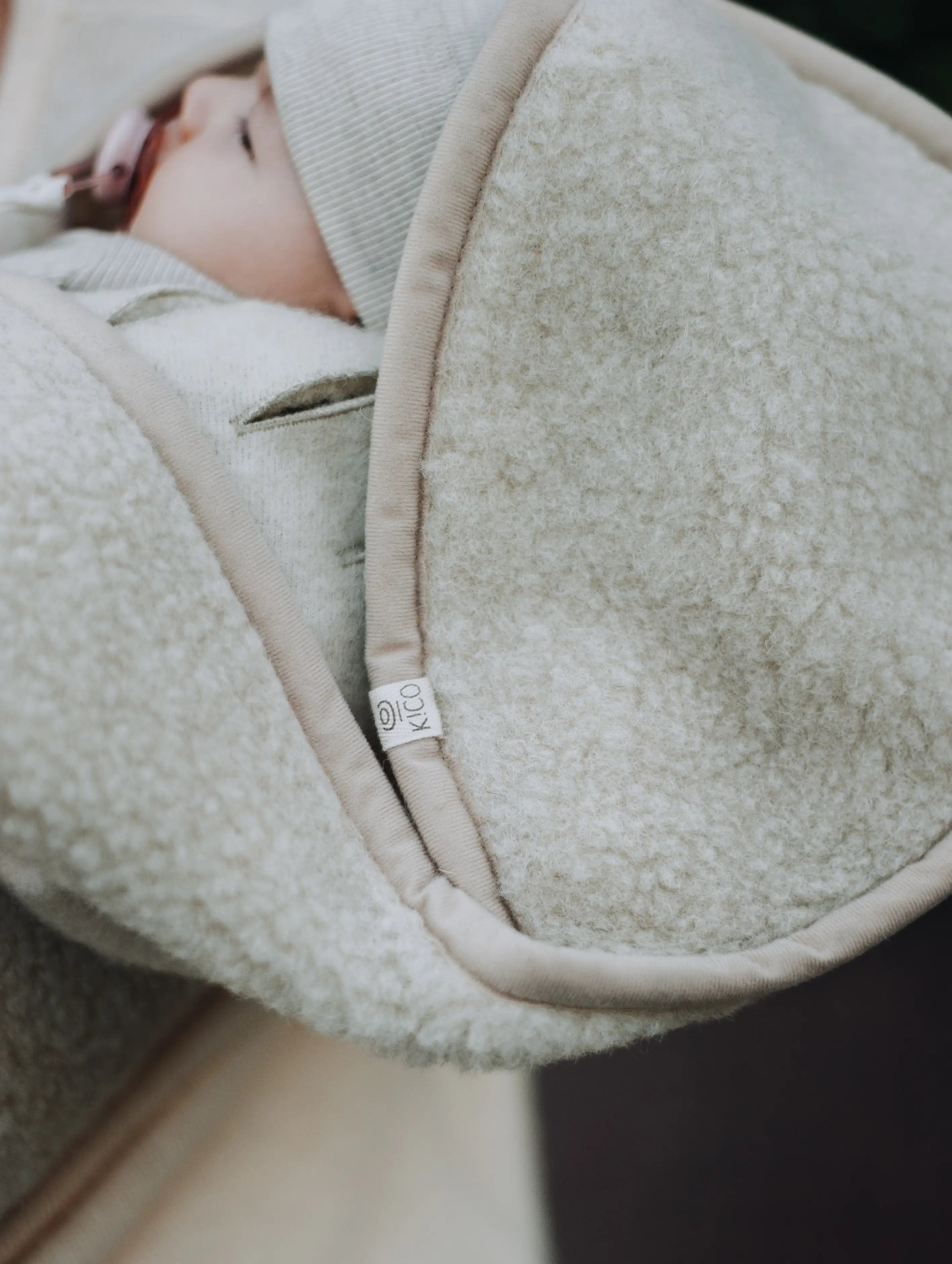 hoofd van een baby met een speen in zijn mond. Gewikkeld in een wollen deken