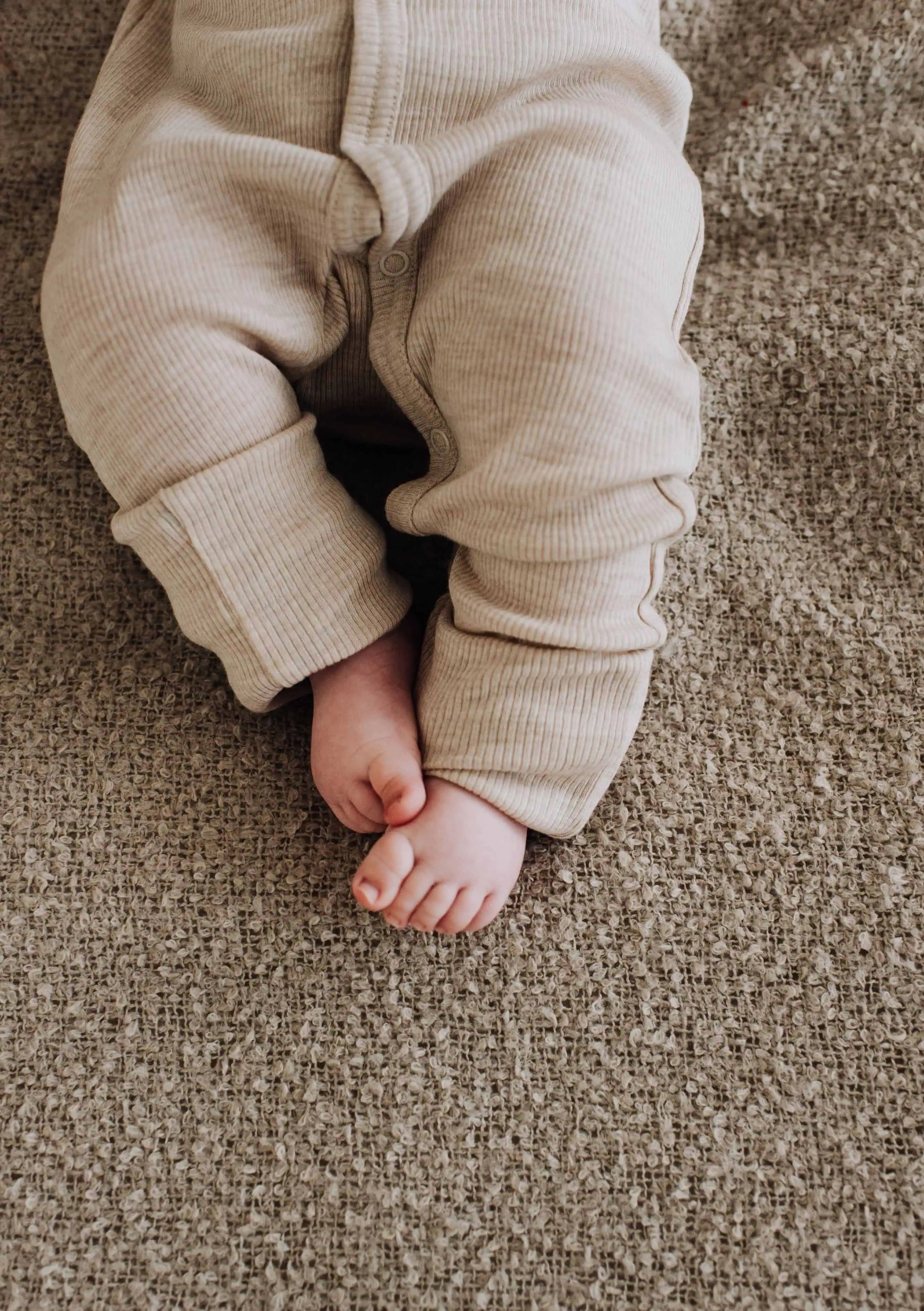 Baby in wollen boxpakje met voetjes. Foto laat enkel de onderste helft van het lichaam zien