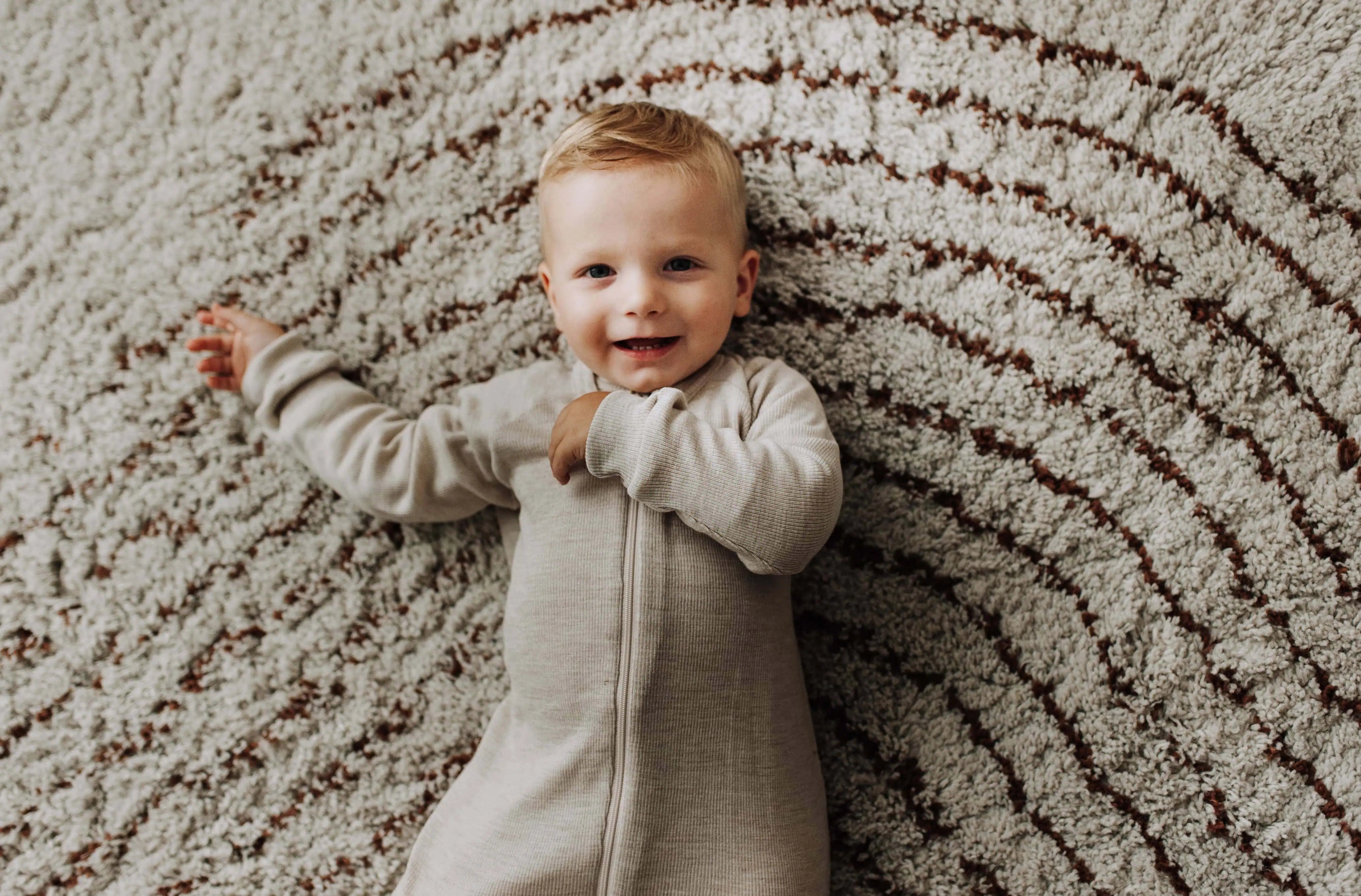 Lachende jongens baby in slaap liggend op tapijt