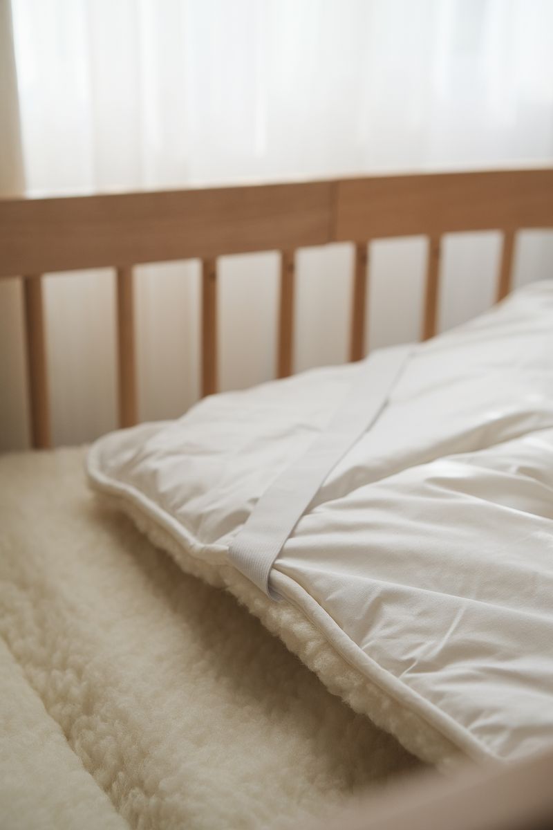 Matrastopper van Kico Label van 100% merinowol, netjes liggend op kinderbed in naturel kleur