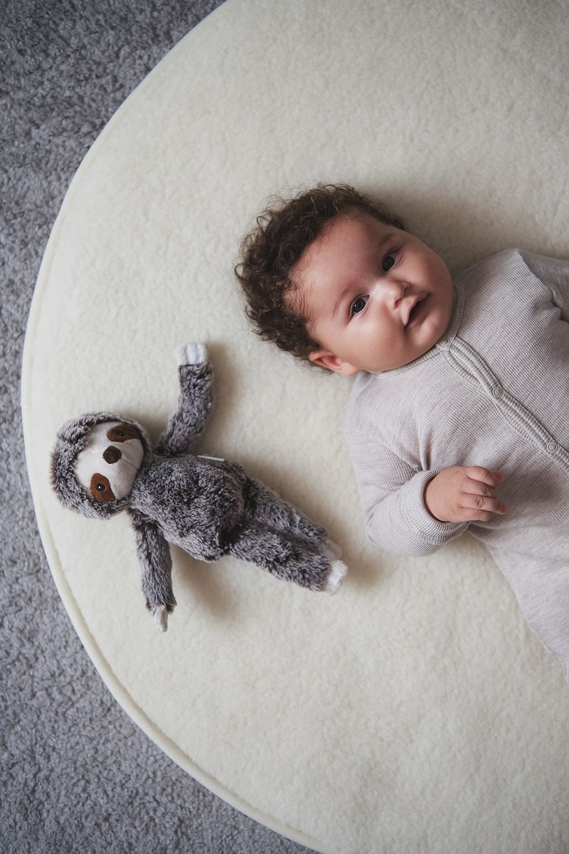 Baby ligt comfortabel op een duurzaam, rond boxkleed van Kico Label in naturel merinowol